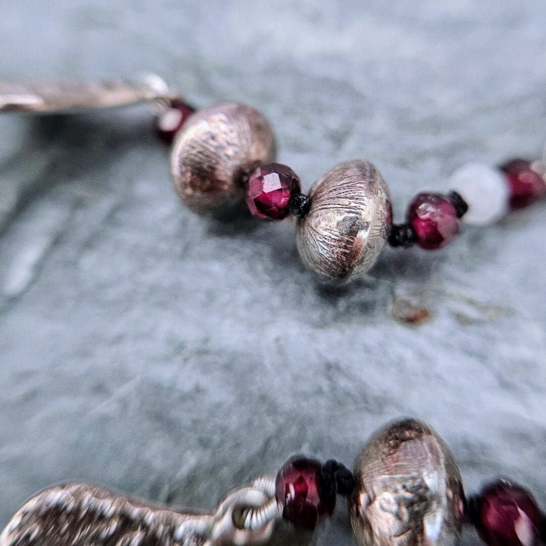 Handcrafted silver heart bracelet with antiqued etched charms, red garnet and moonstone beads on knotted silk, finished with a toggle clasp, bead close up, Isobel Kelly Jewellery, Hants UK
