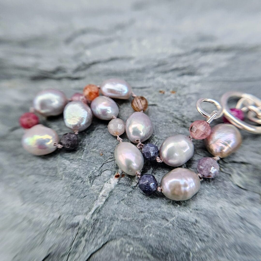Baroque pearl, ruby and sapphire knotted bracelet, silver toggle, grey background beads, Isobel Kelly Jewellery