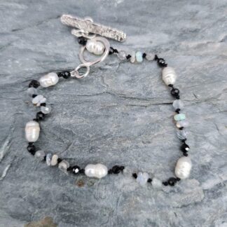 White seed pearl, black spinel, Ethiopian opal and labradorite bracelet, grey background, Isobel Kelly Jewellery