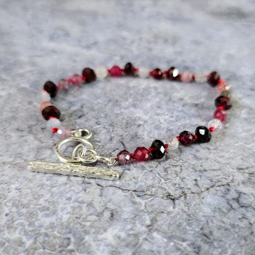 Spinel and garnet gemstone bracelet, grey background, side, Isobel Kelly Jewellery