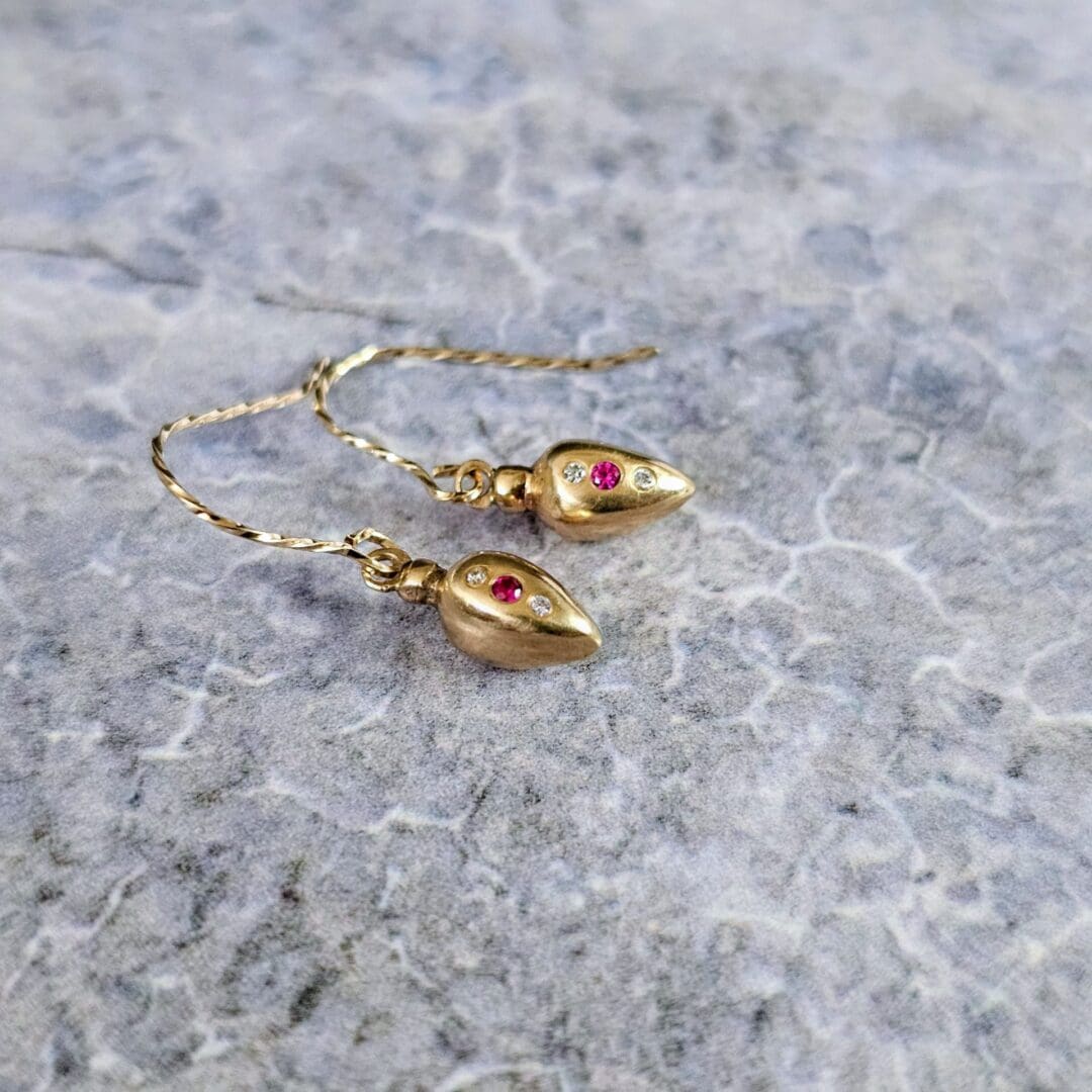 9ct gold drop earrings inspired by Roman amphora vessels, set with lab-grown diamonds and a central pink ruby, featuring twisted gold hooks. Side grey stone. Isobel Kelly Jewellery, Hants UK