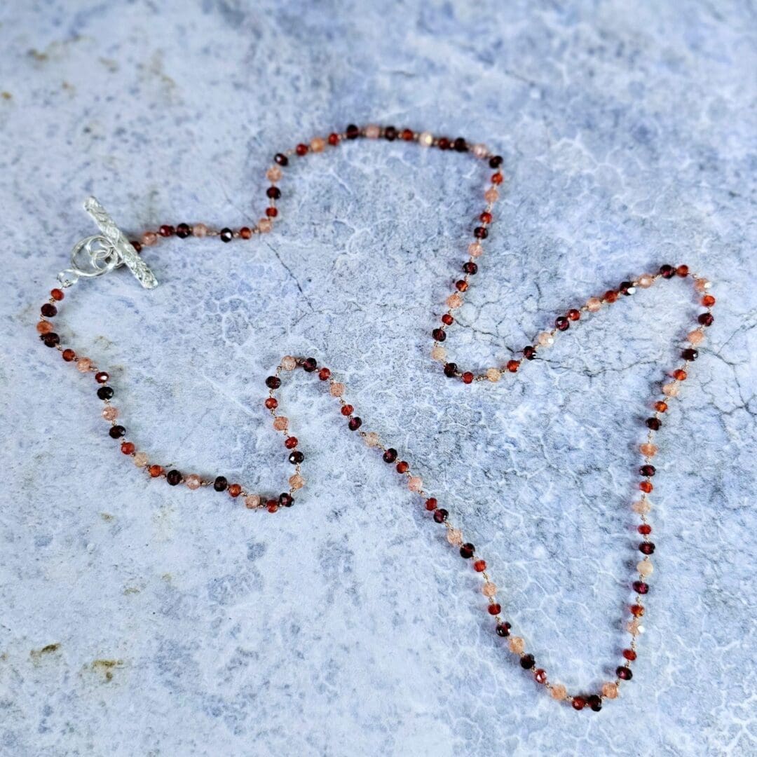 Garnet, sunstone and carnelian gemstone necklace, etched silver toggle, grey background full, Isobel Kelly Jewellery