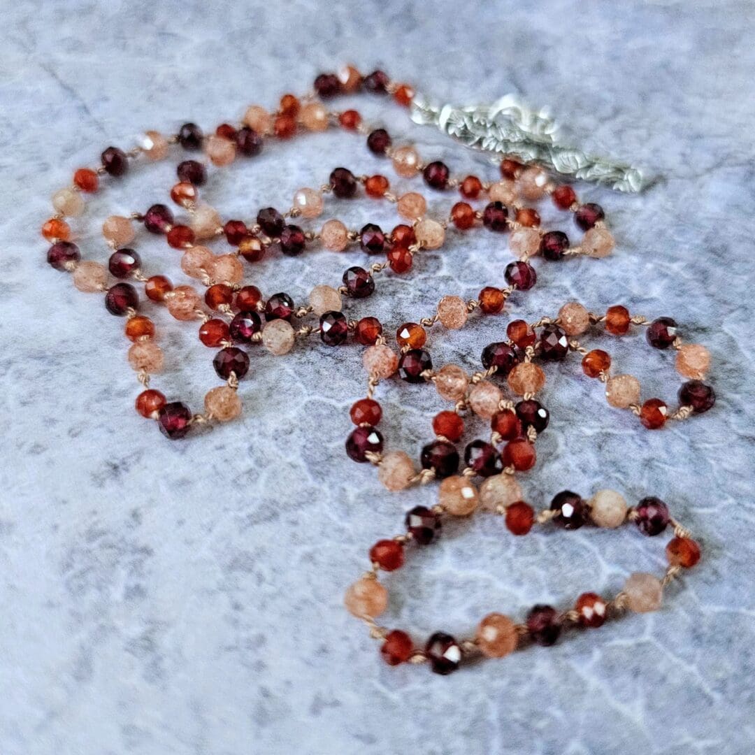 Garnet, sunstone and carnelian gemstone necklace, etched silver toggle, grey background beads, Isobel Kelly Jewellery