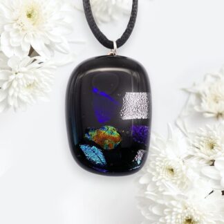A black pendant featuring colorful flecks of blue, green, and orange, surrounded by white flowers.