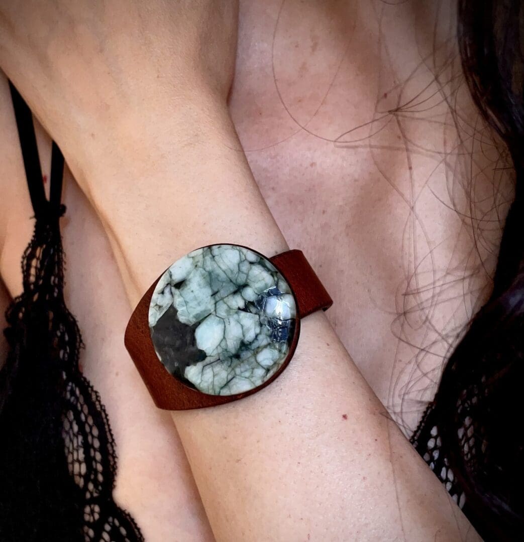 Brown leather bracelet with a large Emerald centrepiece worn on the wrist of a lady