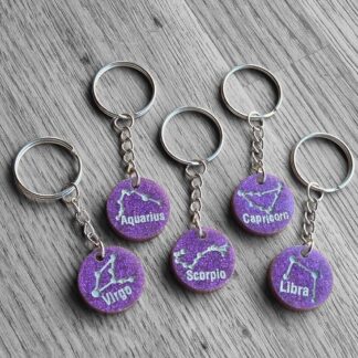 Purple resin zodiac keychains on wooden background