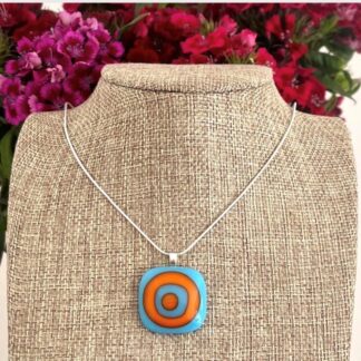 Bright turquoise and orange alternate squares of fused glass forming a beautiful pendant. On a sterling silver bail with silver chain or black faux suede