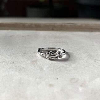 A small delicate ring with a floral bud pattern lies on top of an open book.