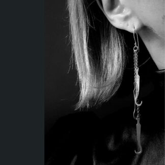 a closeup of an ear of which hangs three chains and a dissection hook on the end of each.