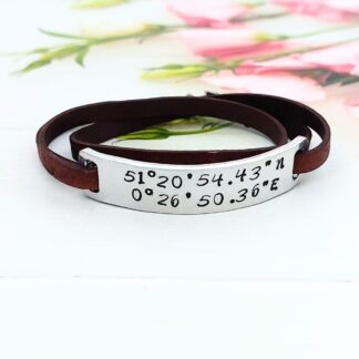 A 12 x 60mm aluminium bar handstamped with personalised coordinates on a flat leather wrap bracelet