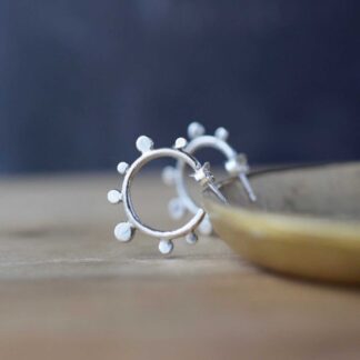 silver hoop earrings with dot design rest on a brass dish