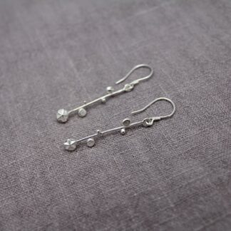 stering silver drop earring with hook back, detailing long bar granulation, discs and a starburst at base.