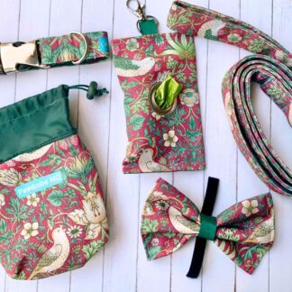 Flat lay of handmade dog accessories in William Morris design. Items are a dog collar, lead, bow tie, treat pouch and poo bag pouch in crimson.