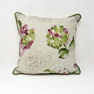 A floral print cushion with a green braid edging.