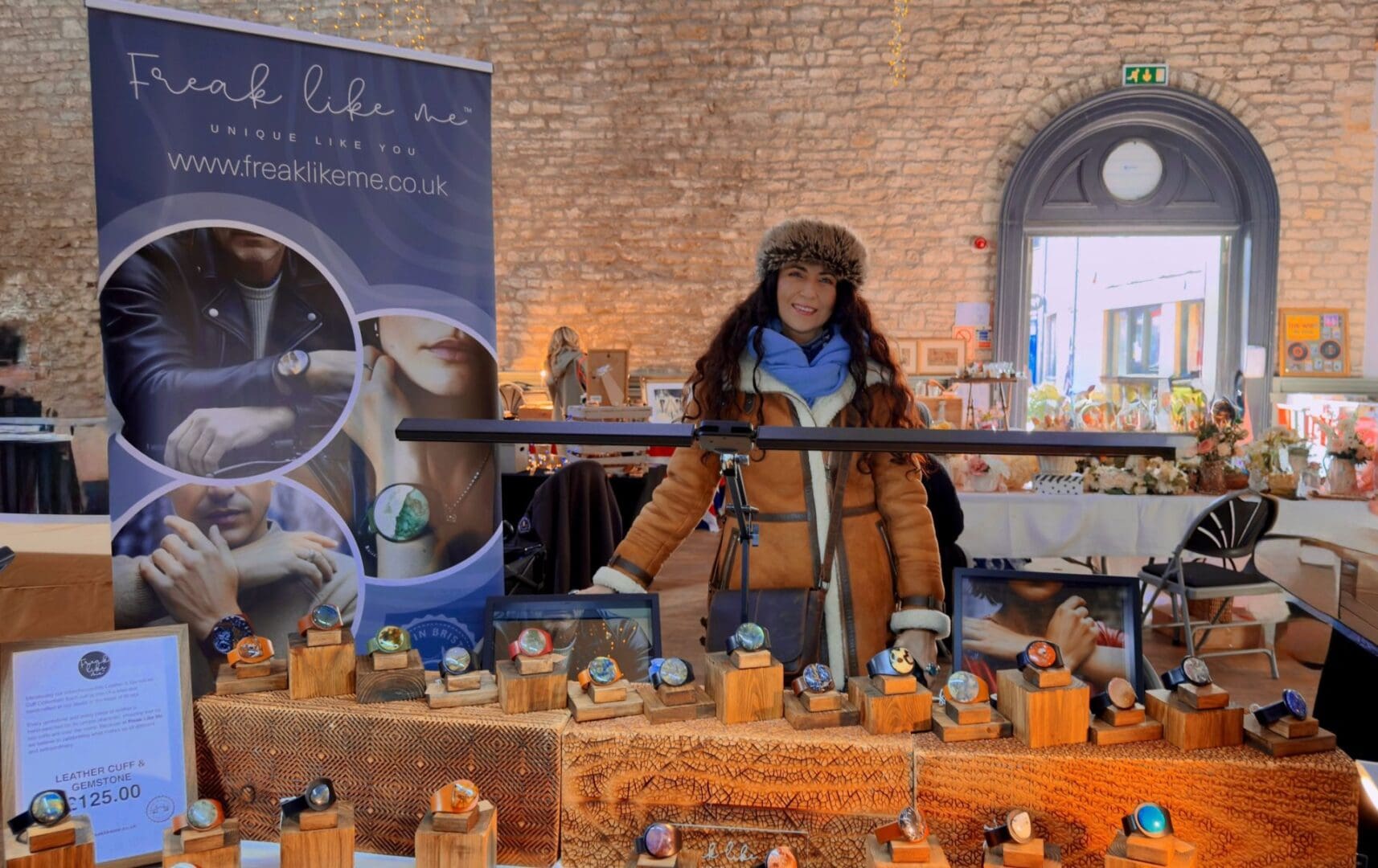 Mila -the artist behind Freak Like Me standing behind a stand at the Cirencester Corn Hall Vintage and Artisan Market. The stand is displaying many leather and gemstone bracelets, handcrafted in Bristol, UK.