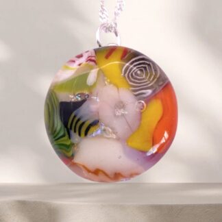 A vibrant, round pendant made of glass featuring colorful designs and bubbles, suspended on a delicate chain.