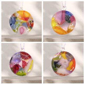 Colorful handmade dichroic glass pendants featuring intricate mosaic designs, displayed on a simple background, showcasing unique artistic patterns.