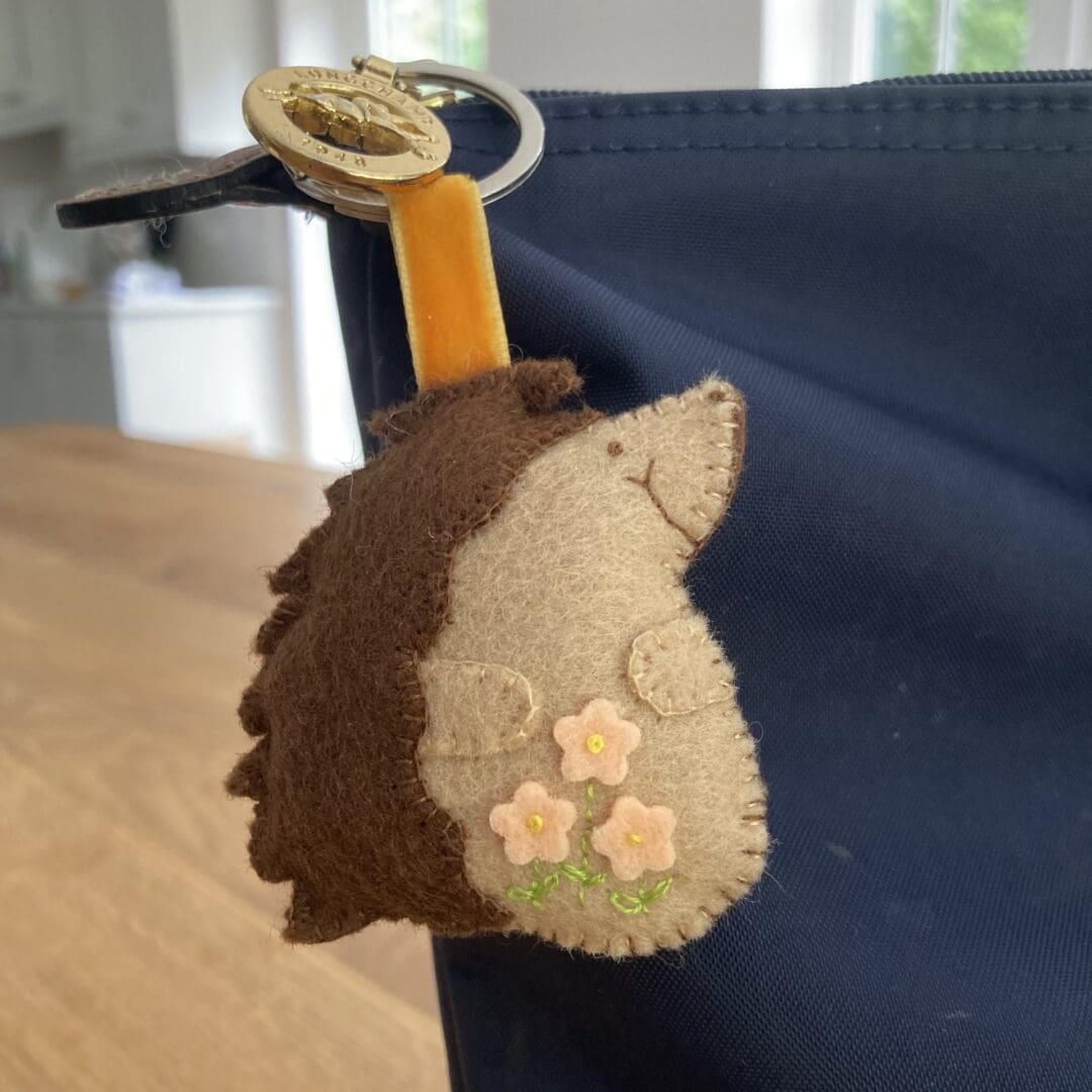 Pretty hedgehog bag charm with peach flowers and peach velvet ribbon attaching it to the slip ring