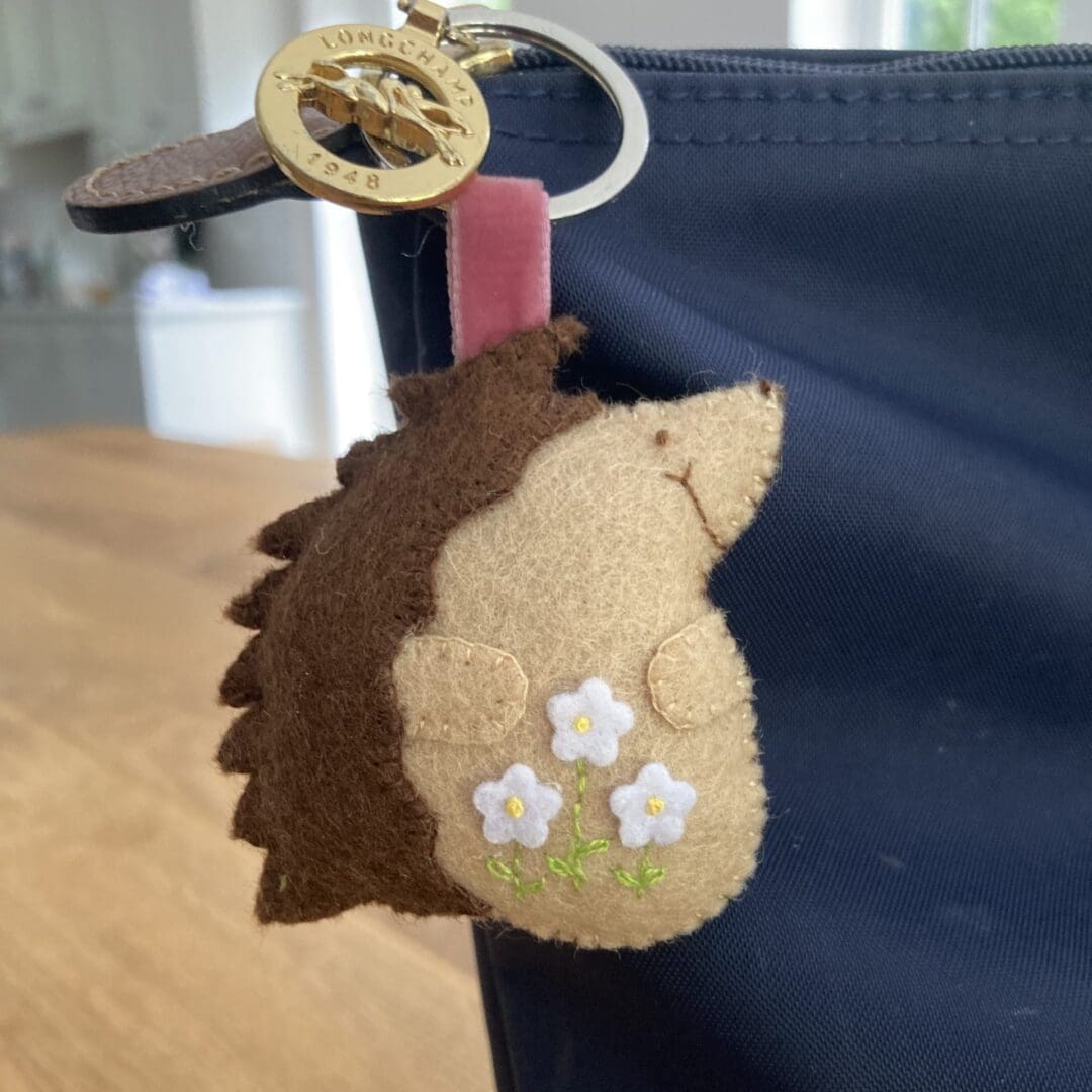 Handamde felt hedgehog with a velvet ribbon attaching it to a slip ring so it can be attached to a bag