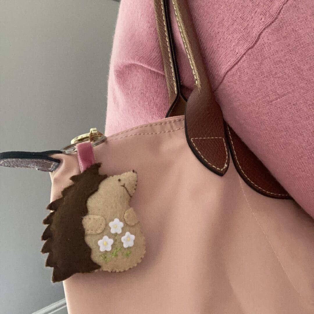 Hedgehog bag charm is on a pink bag being carried over my shoulder