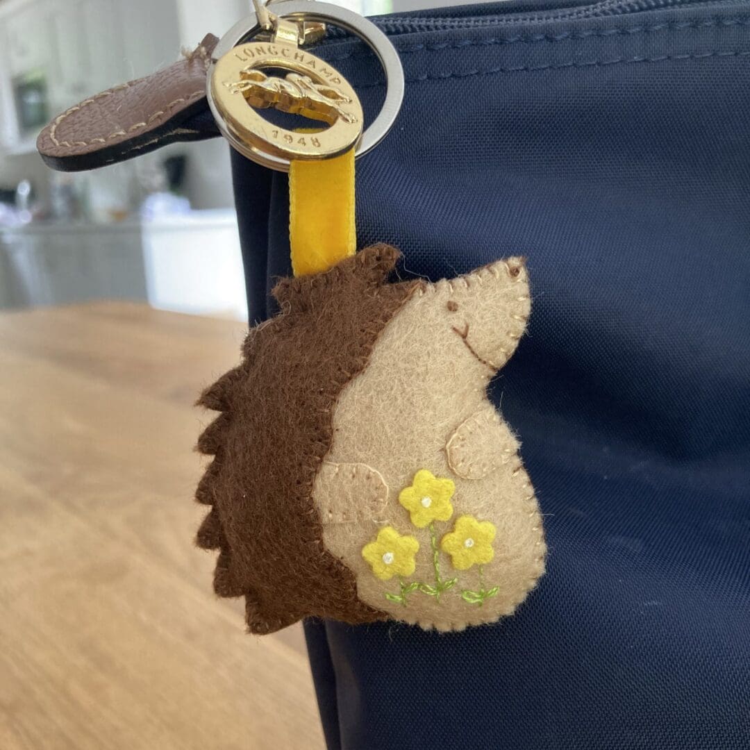 Hedgehog bag charm with yellow flowers and a yellow velvet ribbon attaching it to the slip ring