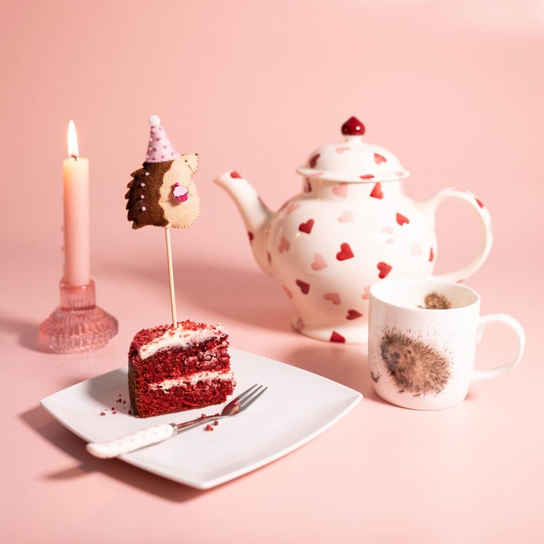 BIrthday cake with a hedgehog cake topper with a cup and pot of tea