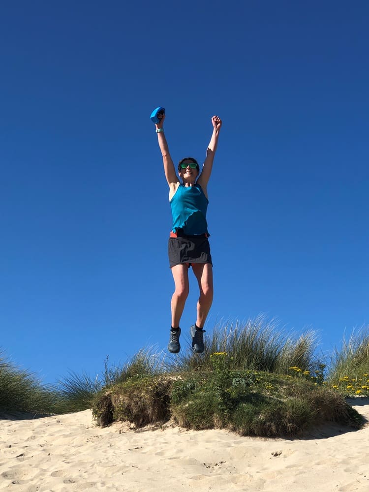 Gill, the maker behind Arvor and Mor Jewellery, is jumping in the air in the sand dunes where she loves to run