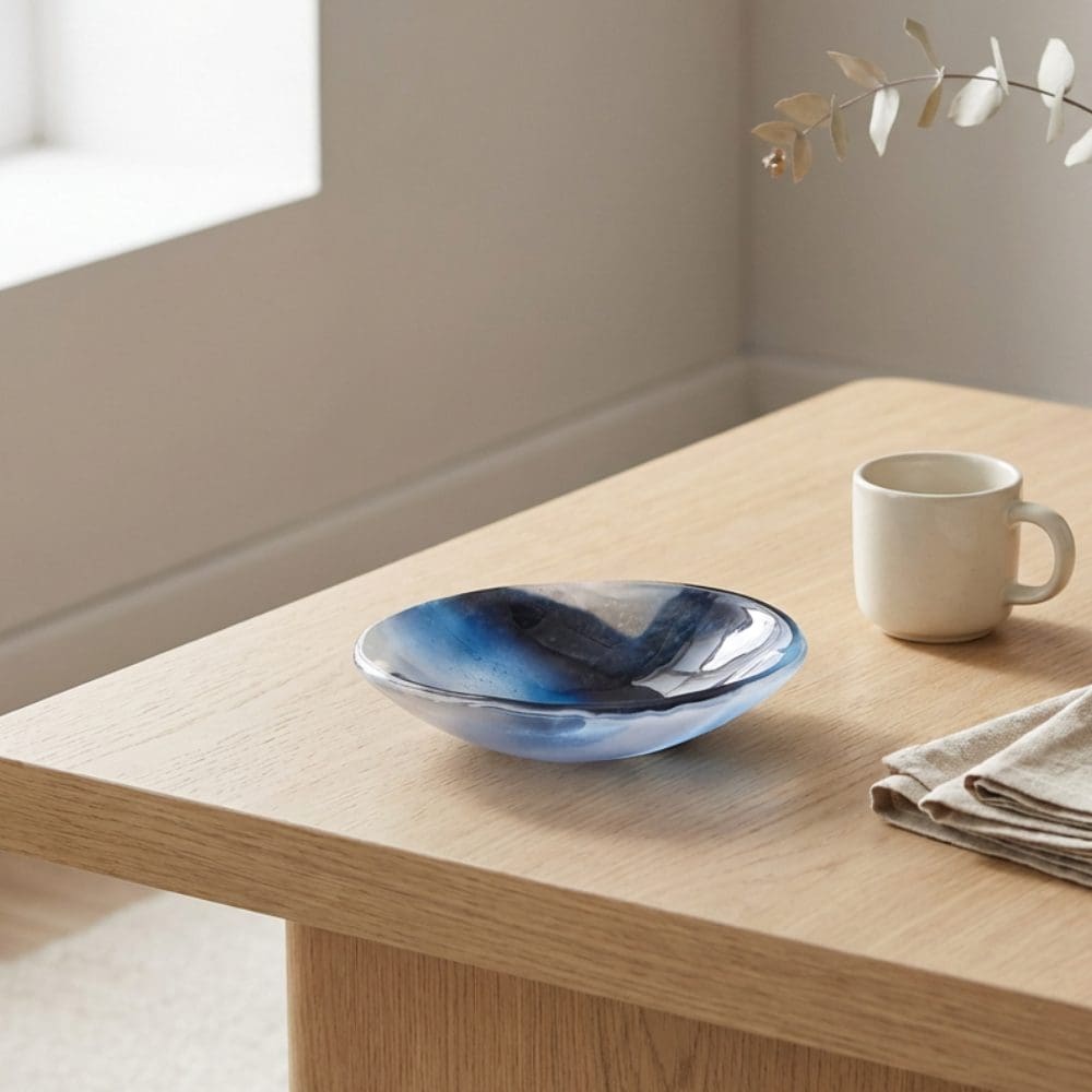 Minimalist blue glass decorative bowl in modern home setting, handmade with subtle marbled effect.