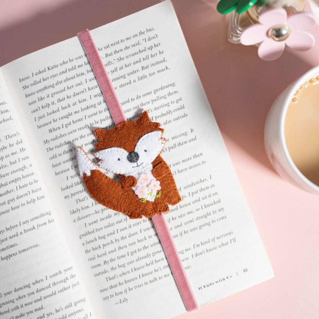 Handmade felt fox on a pale pink velvet ribbon which will hold your place in a book. The fox is holding 3 pale pink flowers