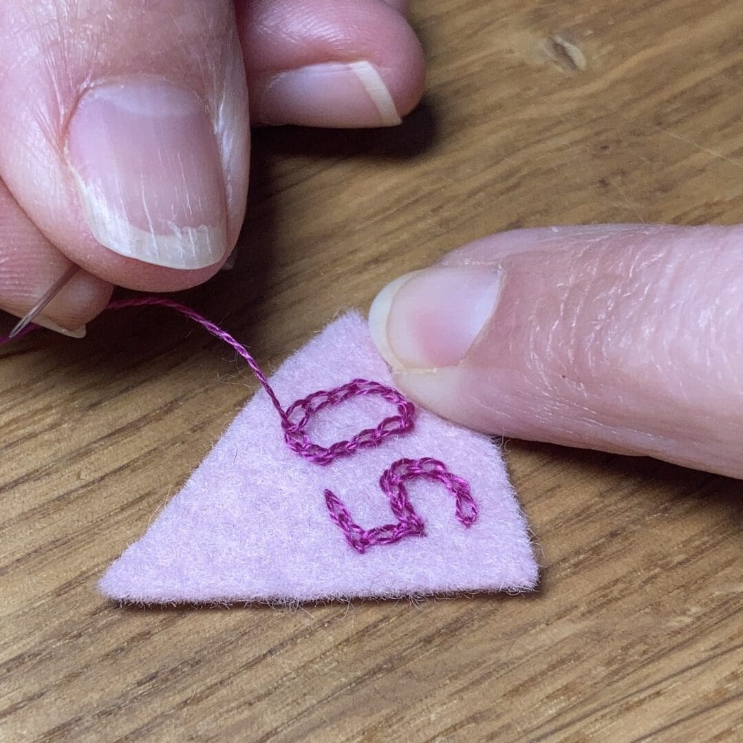 Hand embroidering 50 onto a birthday party hat