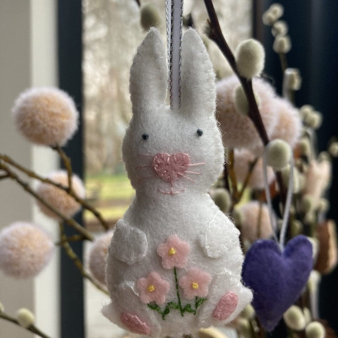 White handmade felt bunny with pink flowers, nose, whiskers and paws