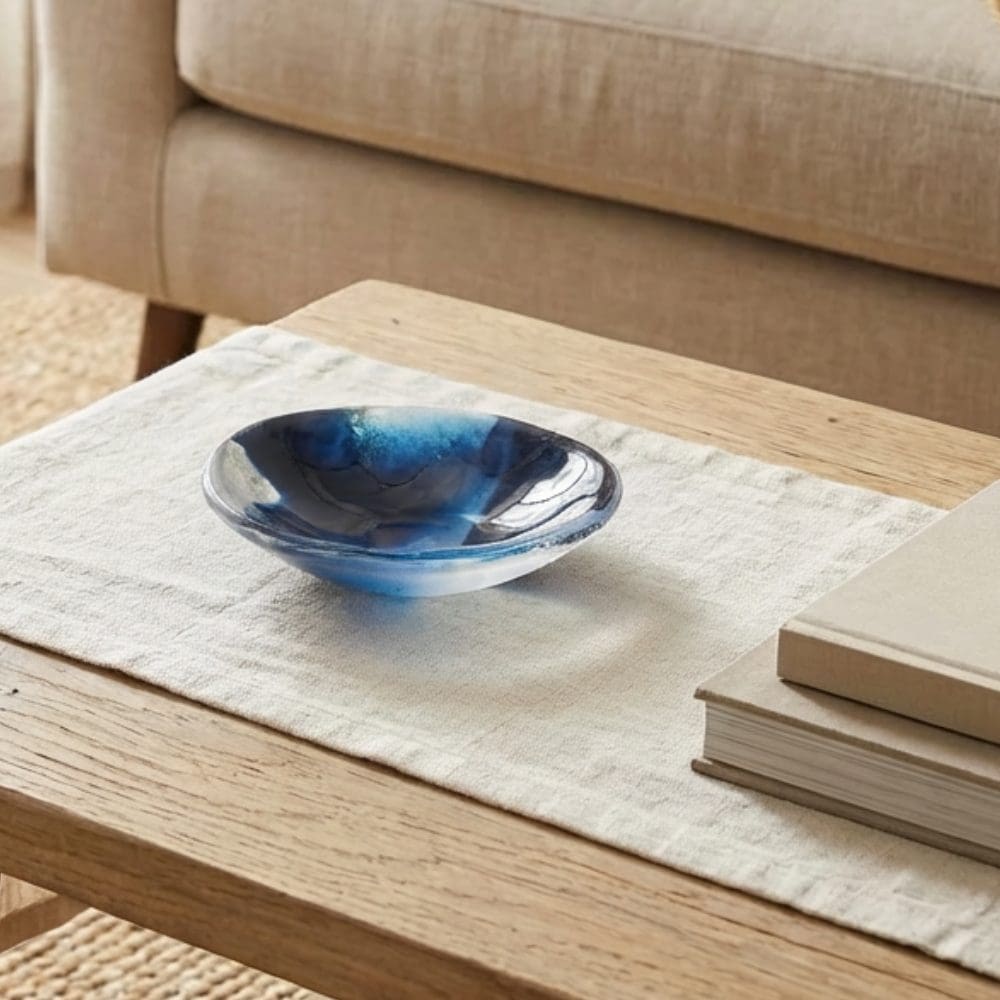 Coastal style handmade blue glass trinket bowl with ocean-inspired marbled design on a neutral table.