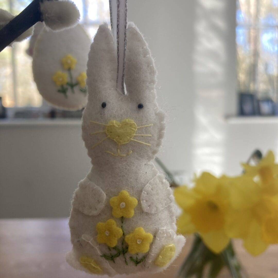White bunny with yellow note, whiskers and flowers