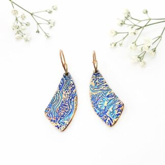 A pair of copper handcrafted drop earrings that have a web effect texture with a twisted pear shape. They have rose gold plated ear wires and are displayed a white background.