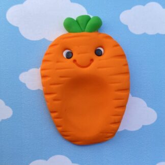 Handmade polymer clay carrot worry stone. Made with a vibrant orange and green stalks on its head. includes a bright smiling face and a thumb indent to aid with anxiety.