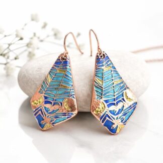 A pair of copper drop earrings in a domed extended triangle shape, textured a nd hand painted in turquoise shades of metallic paint. They have rose gold plated ear wires and displayed on a white background with a white gift box above it.