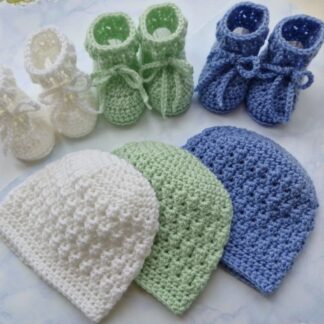A selection of coordinated handmade crochet baby hat and matching booties sets in a soft textured stitch. In colours white, tea Green and periwinkle blue