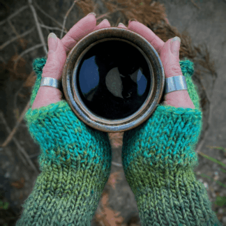 Green rainbow hand knitted fingerless armwarmers pictured round the campfire