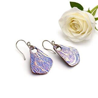 A pair of handcrafted triangle shaped copper drop earrings with a large hole for the sterling silver ear wires. Hand-painted blue metallic paint, these textured earrings are displayed on a white background.