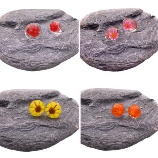 Four pairs of colorful flower-embedded handmade glass earrings displayed on a textured gray stone surface.