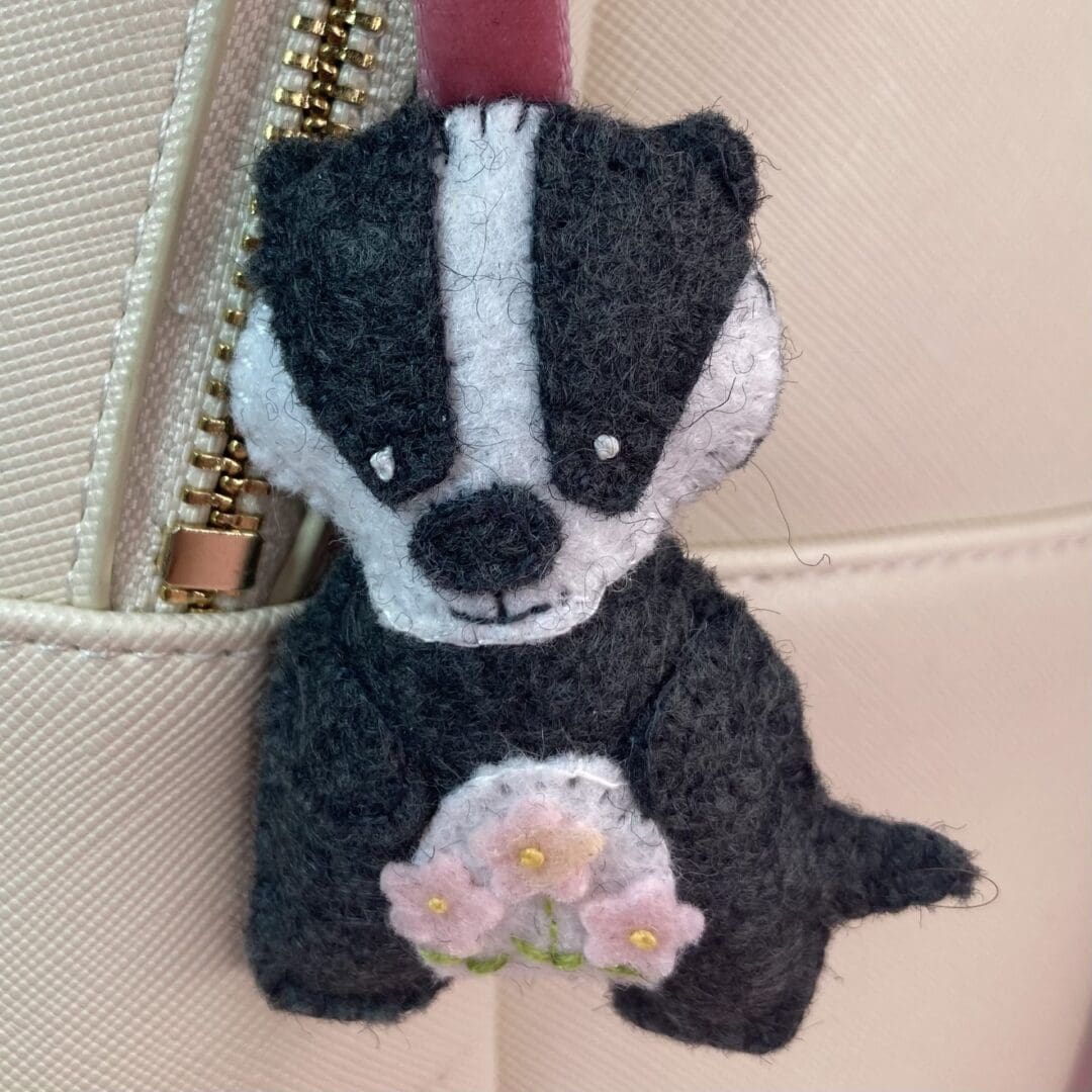 Bagder bag charm on a cream backpack