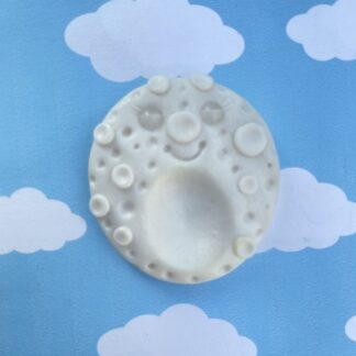 Handmade polymer clay moon worry stone. shimmering pearl white kawaii style, with a cute smiling face, with craters and raised ares and an indent to rub with your thumb when youre feeling anxious