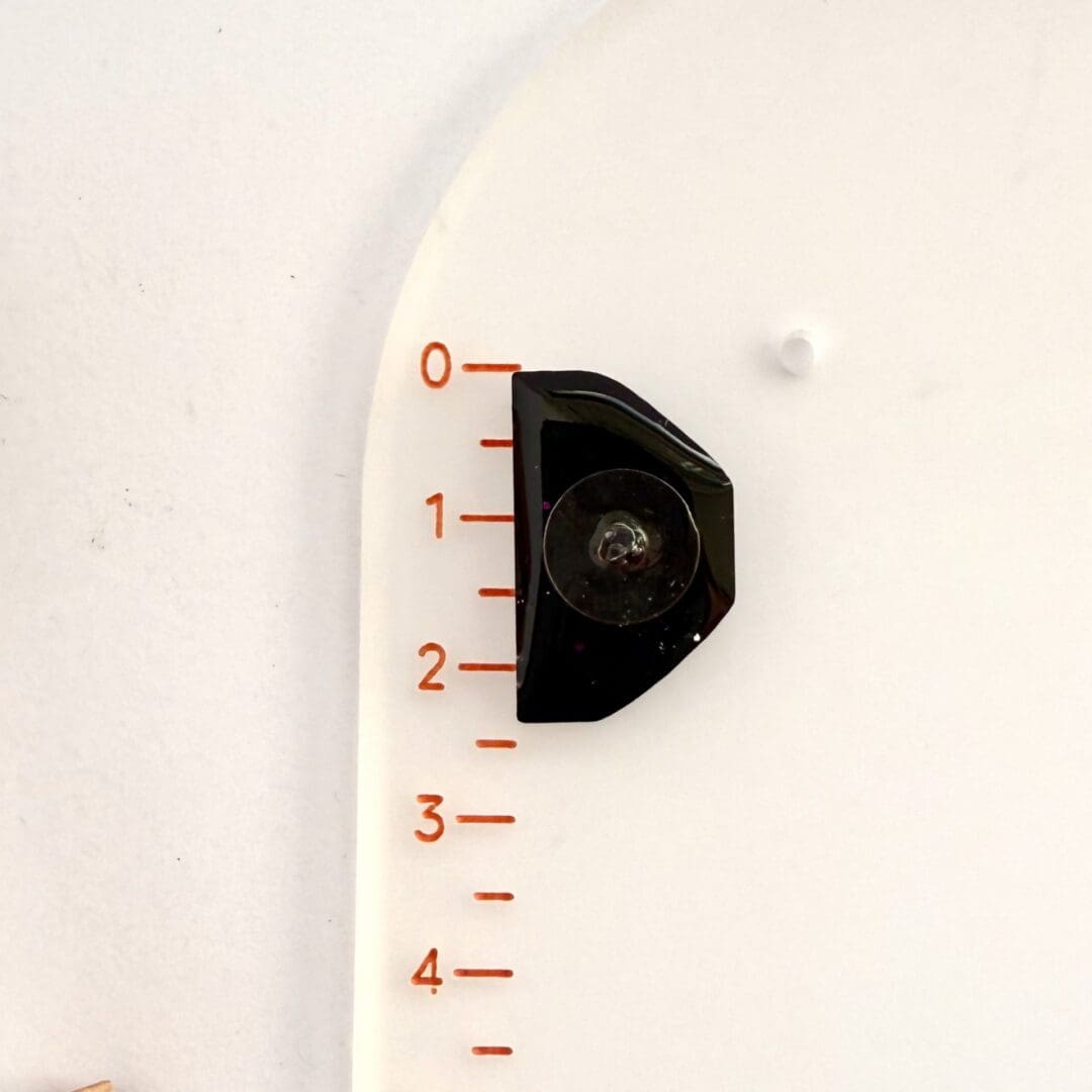 Positive pants pin badge (dark pink glitter) shown in reverse against the ruler to show size