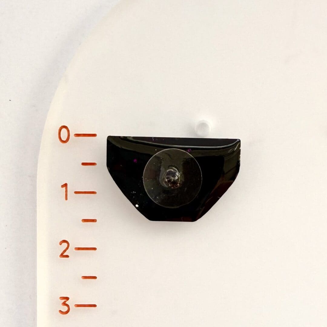 Positive pants pin badge (dark pink glitter) shown in reverse against the ruler to show size of side