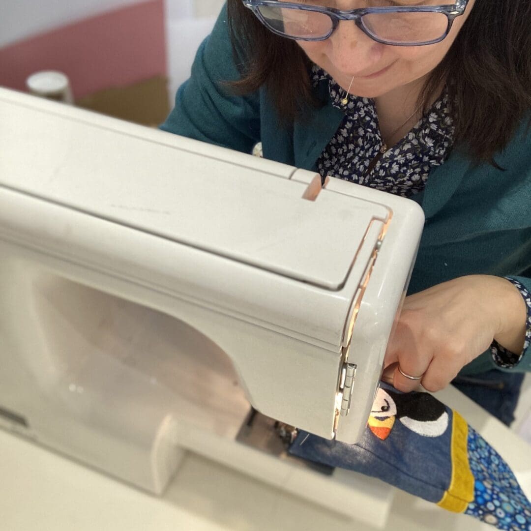 Photo of me sewing a puffin glasses case together on my sewing machine