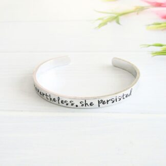 A hand-stamped adjustable 6mm width aluminium bracelet, hand-stamped with the inspirational words, nevertheless she persisted