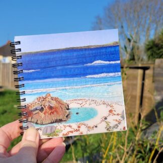 Spiral bound notebook with plain and lined paper. Art work on the cover is a print of an embroidery of a rockpool on a beach 12 x 12 cm