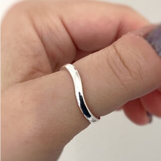 Silver wavy ring worn on a thumb. Close up image.
