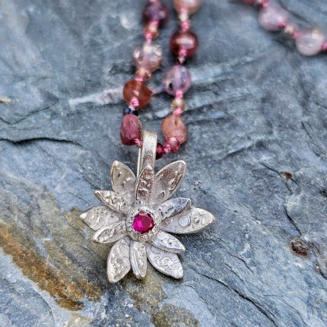 Spinel bead necklace with an etched silver flower pendant set with a small lab ruby at the centre, Isobel Kelly Jewellery