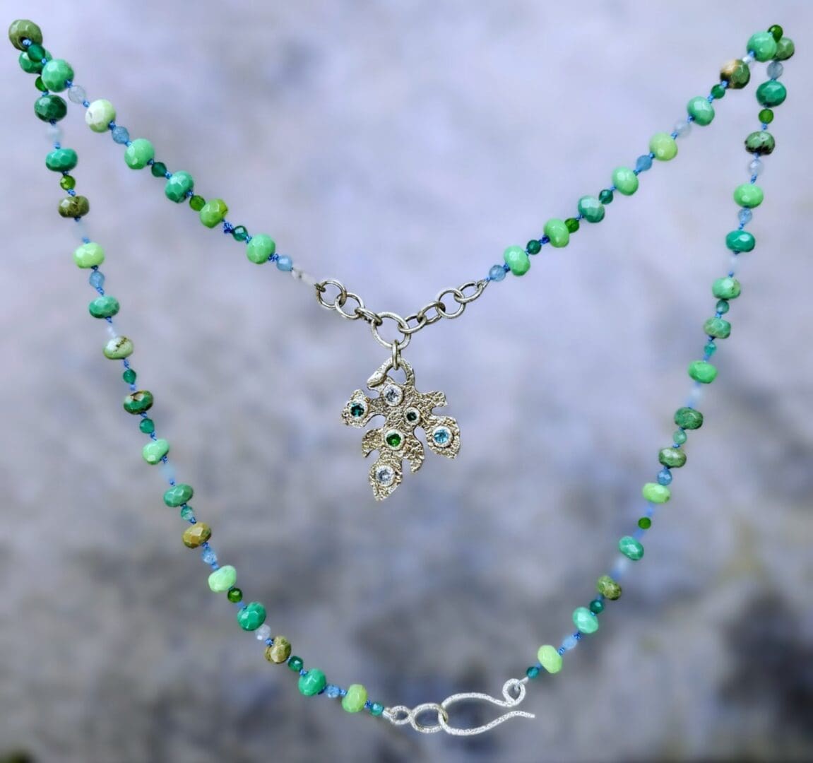 Silver leaf pendant set with lab emerald, topaz, tsavorite and spinel, hanging, Isobel Kelly Jewellery
